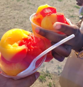 Me and my friend holding Mango and Cherry icies in the sun.