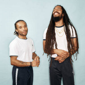 Duo Band Bob Vylan in white t shirts, smiling against a light blue background
