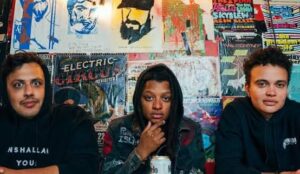 The Band the Muslims sitting in front of a colorful background full of posters